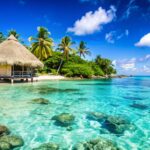 Tropical beach with a thatched hut, clear blue water, and palm trees.