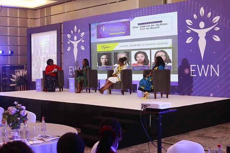 Four women seated on stage during a panel discussion against a purple EWN backdrop.