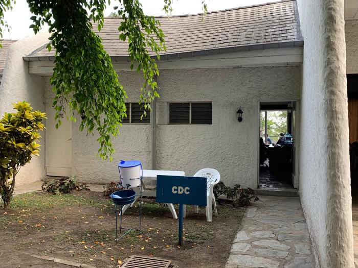 A water container, basin and chair beside a CDC sign outside an office in Goma.